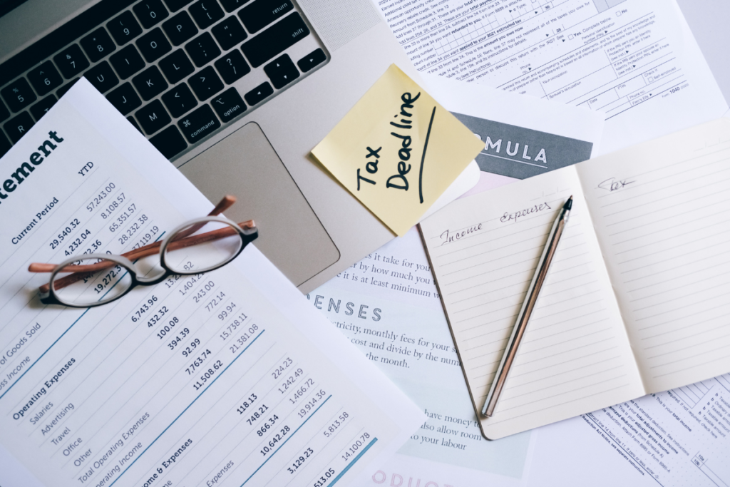 Tax forms, laptop, and notebook on a table with 'Tax Deadline' written