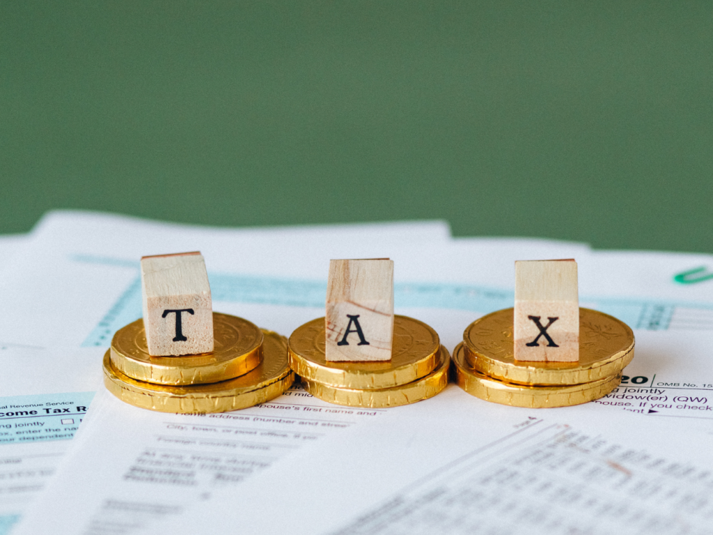 Tax written on cubes with gold coins and tax forms
